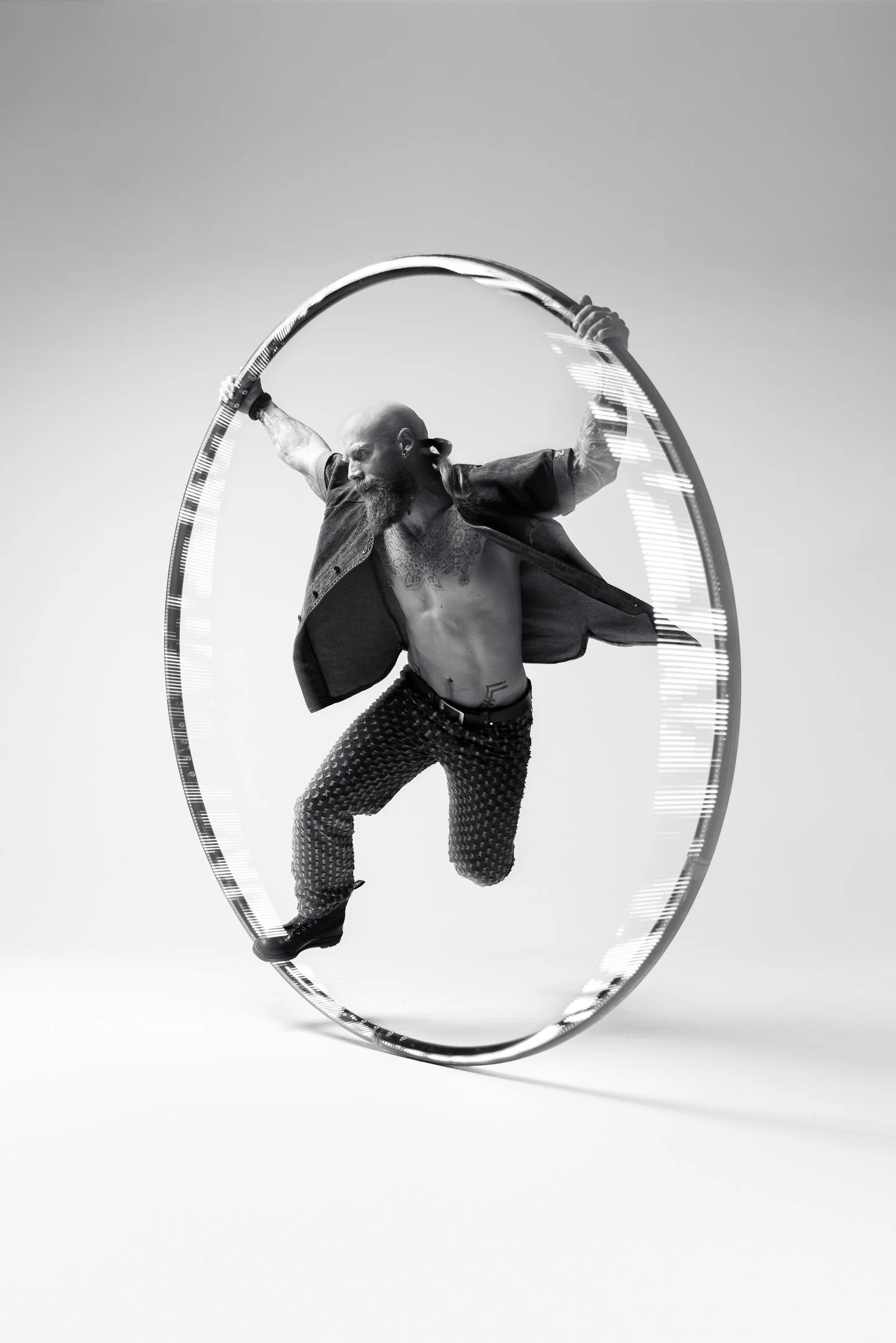 A performer balancing inside a large cyr wheel, holding its rim with both hands.