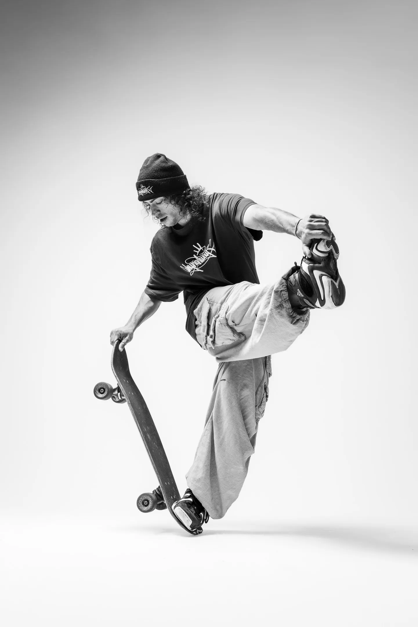 A skateboarder balancing on the tail of the board, holding one foot behind him.