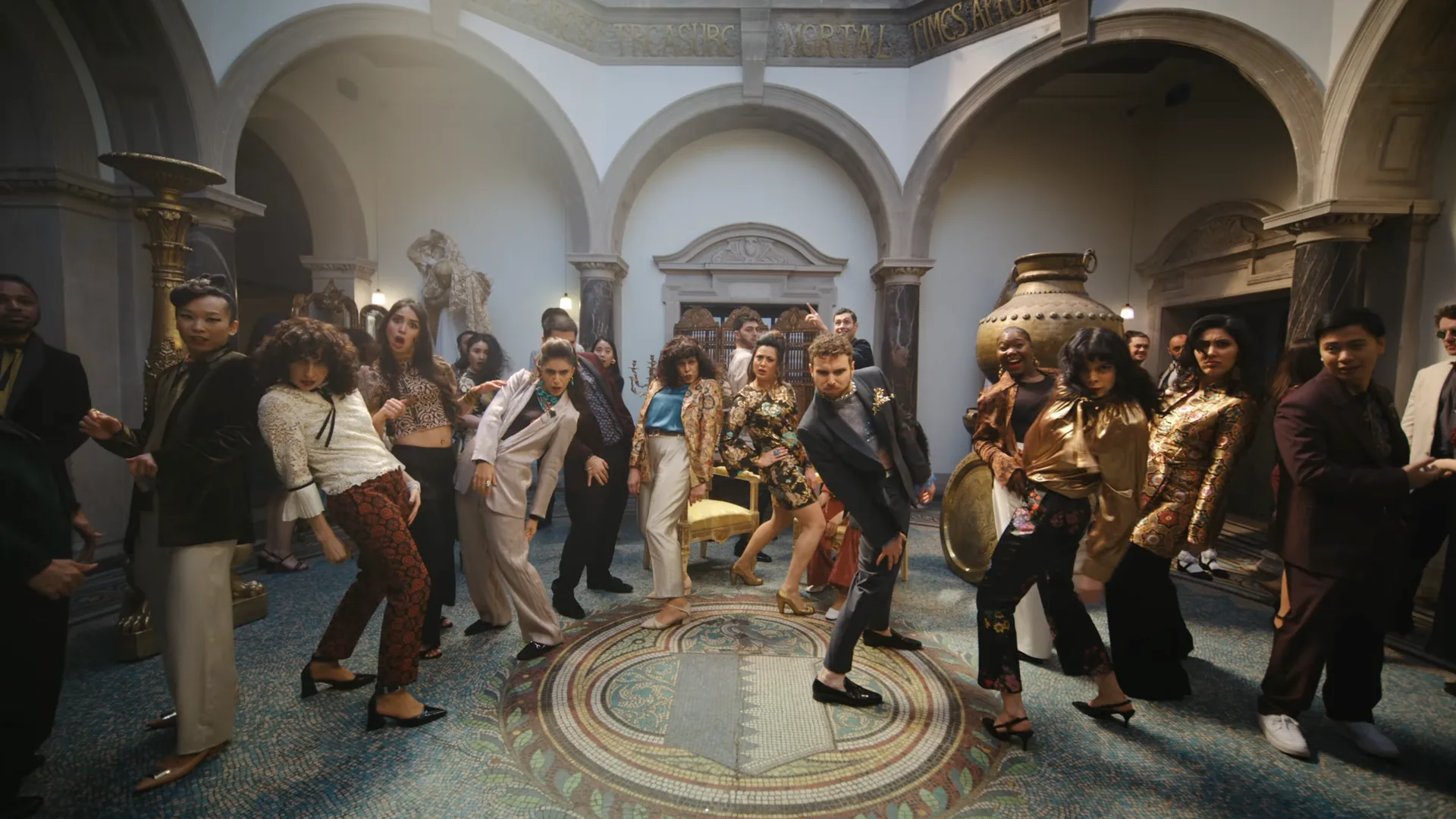 Dancers in 1970s dress mid-step across a mosaic floor in Ed Sheeran’s Azizam video