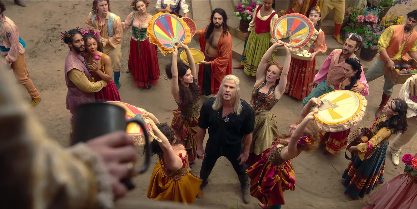Dancers with tambourines circling a singer at a festival on The Witcher