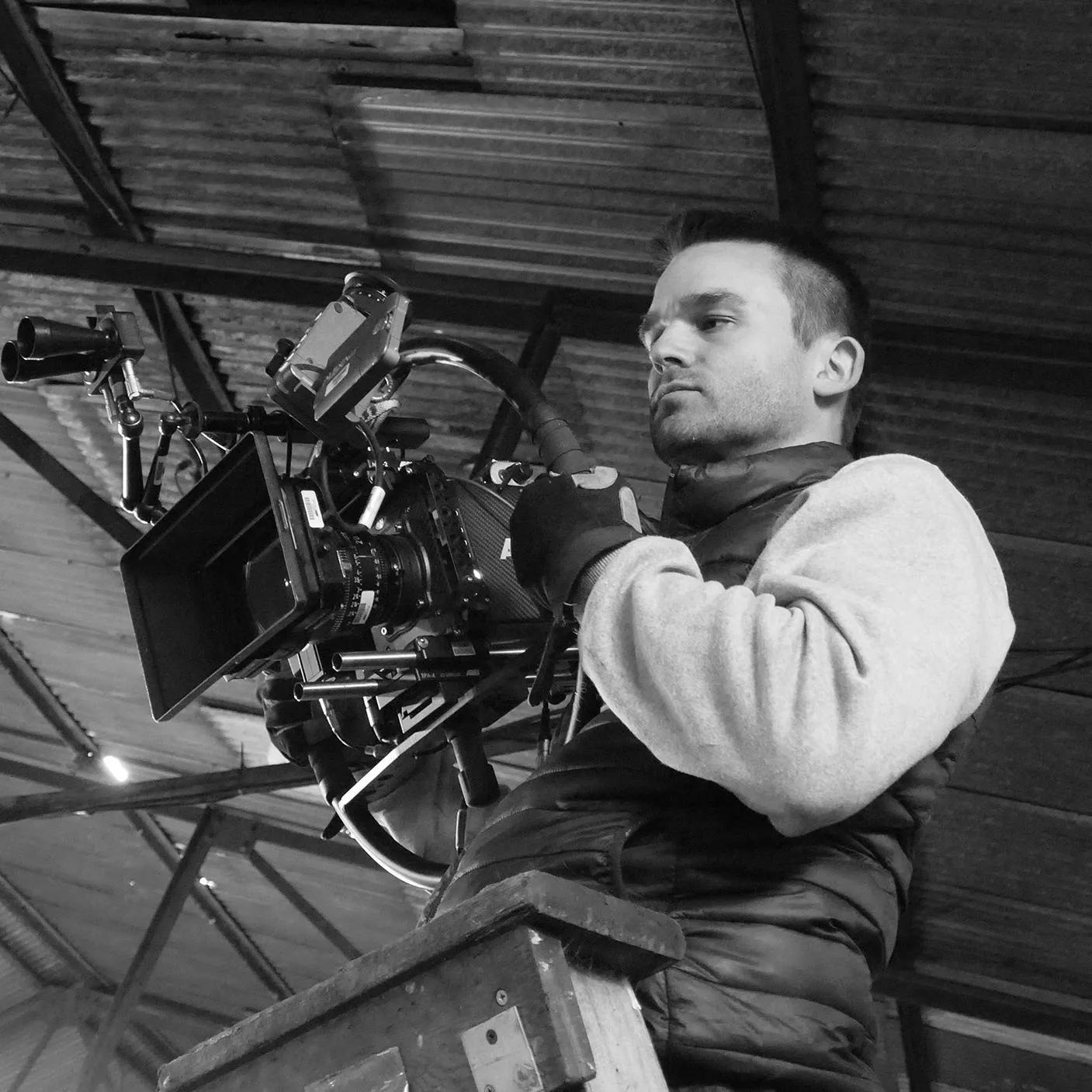 Jude Poyer operating a camera on a crane, looking down the lens.