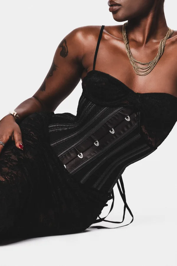 Black and white detail of a model reclining in a boned corset and gold chains