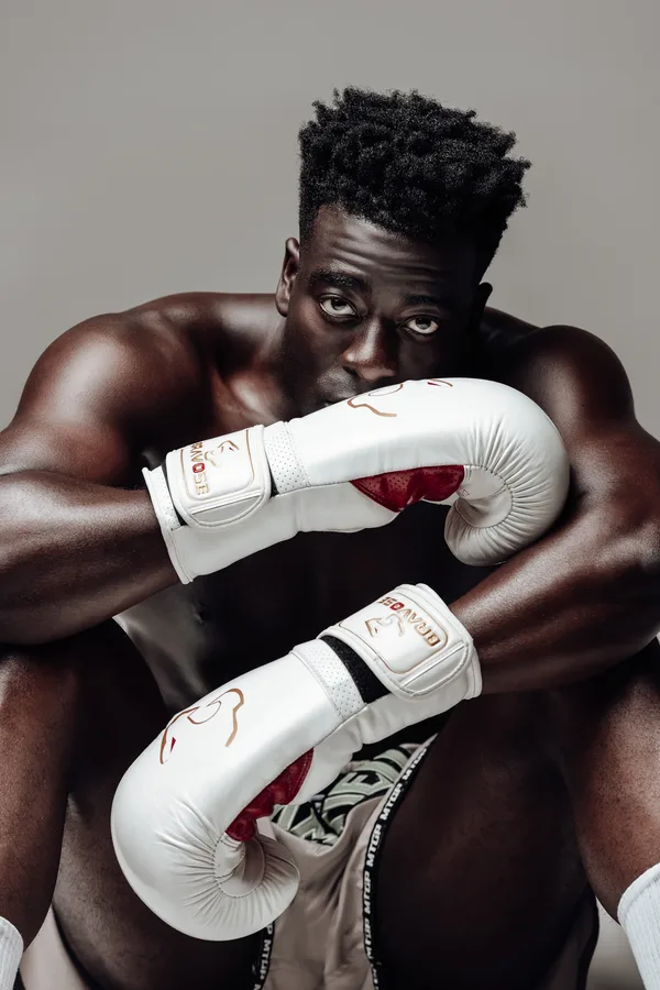 Model seated with white boxing gloves crossed under his chin
