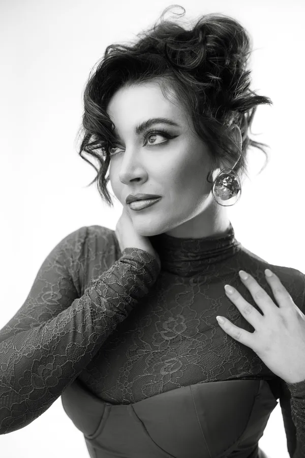 Black and white portrait of a model in a lace turtleneck with a sculptural earring, looking away