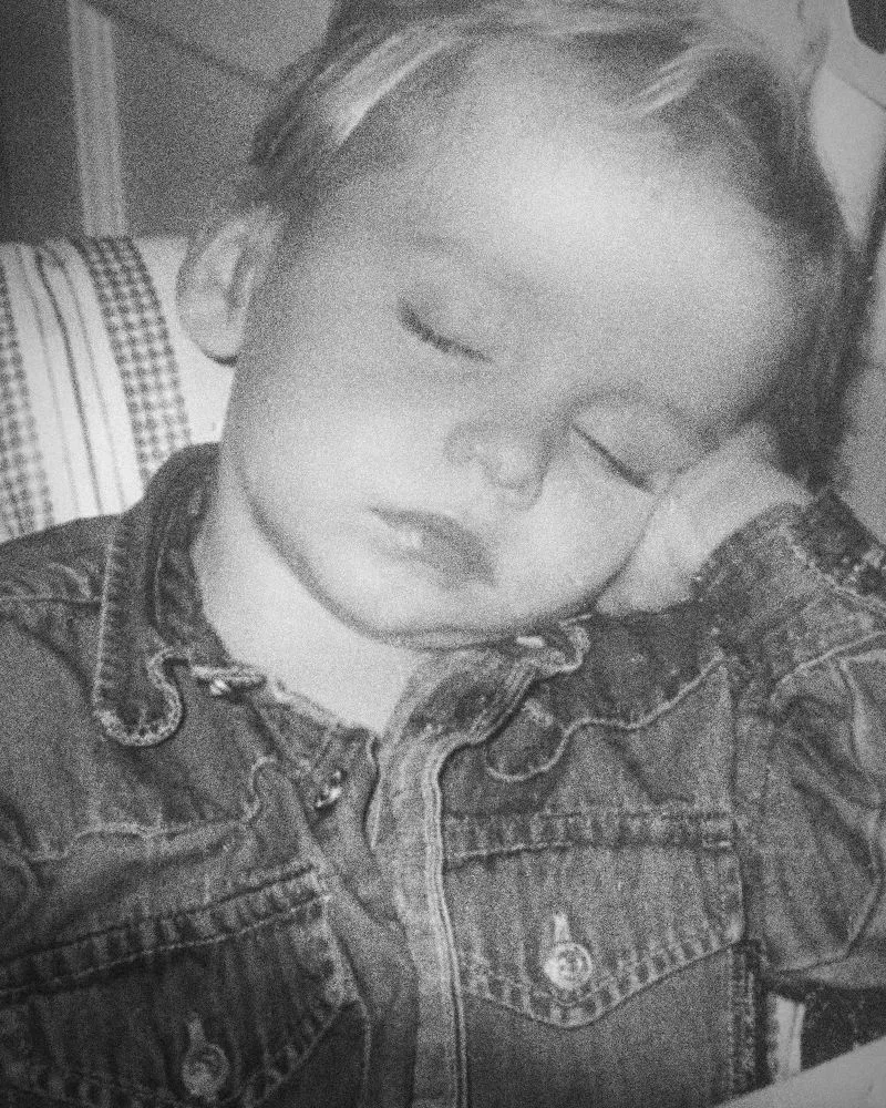 Tyler as a toddler, fast asleep in a denim shirt with his head resting on his hand